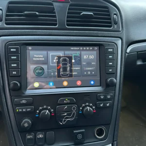 Car interior dashboard with a touchscreen infotainment system displaying navigation, time, and radio info in a modern vehicle interior.